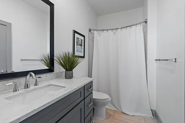 a bathroom with a granite countertop sink a toilet and with mirror