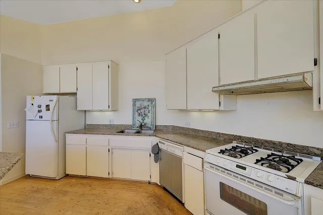 a kitchen with stainless steel appliances granite countertop a stove a sink and white cabinets