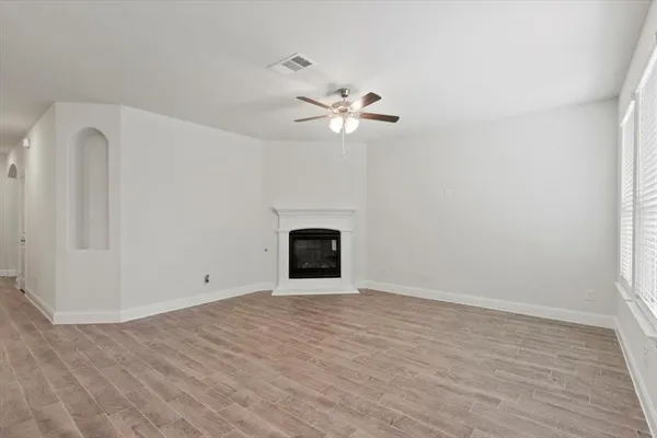 a view of an empty room with a ceiling fan and kitchen view