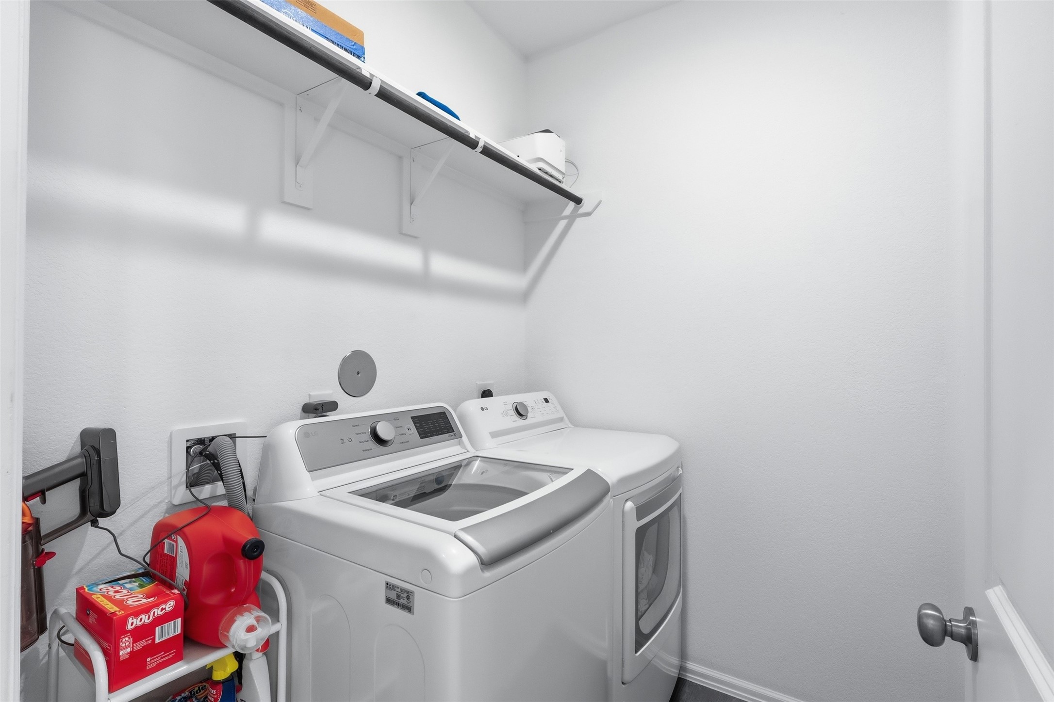3727 Moss Hl Road Rosenberg, TX 77469 - Photo 23 of 32 The laundry room featuring modern washer and dryer units. There's a shelf above for storage, and the space is bright with a clean, minimalist design.