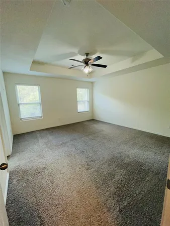 an empty room with windows and ceiling fan