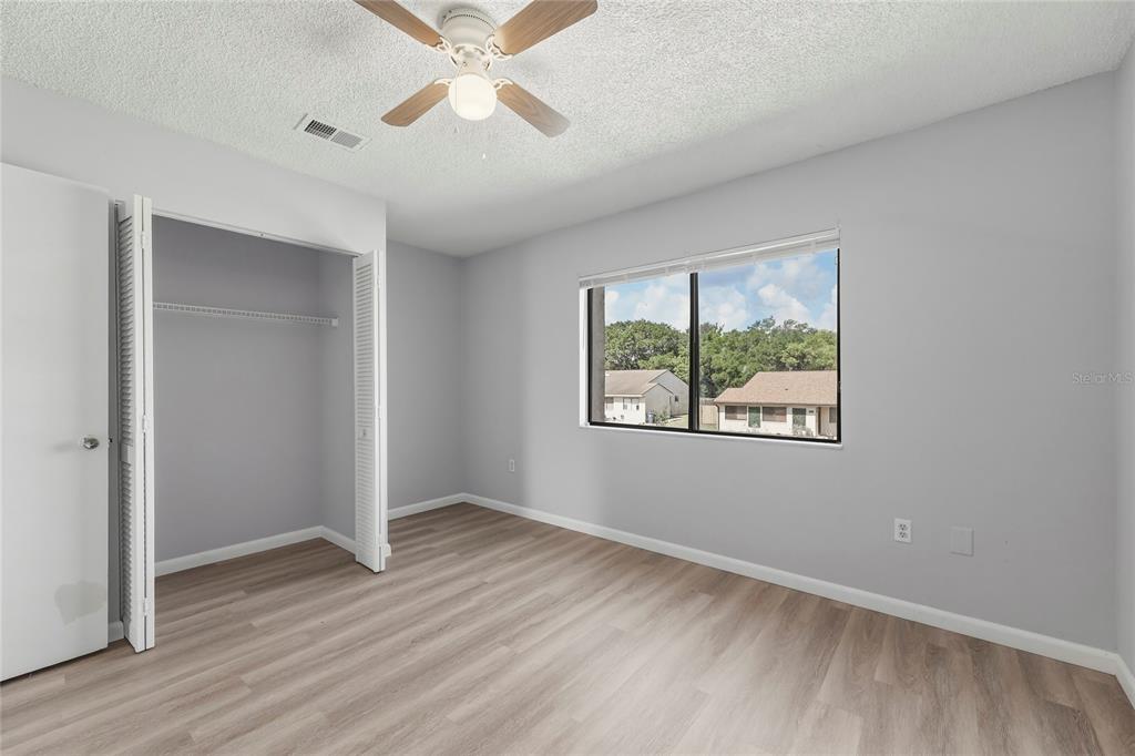 4799 Sisson Road Titusville, FL 32780 - Photo 16 of 23 an empty room with wooden floor chandelier fan and windows
