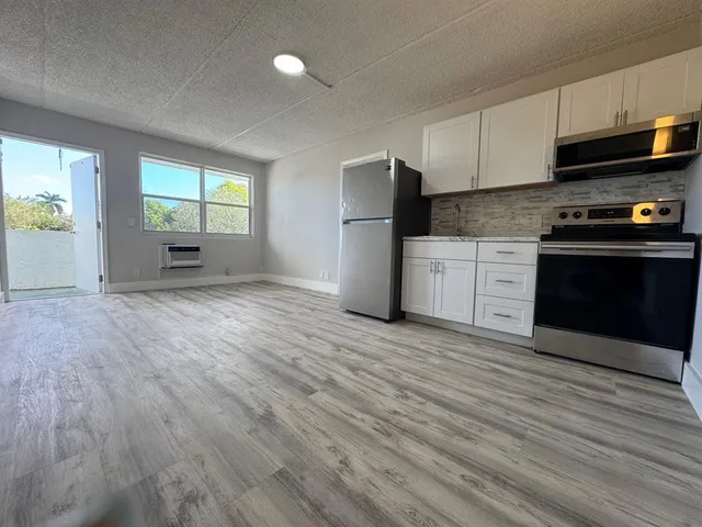 a kitchen with granite countertop a stove a sink and a refrigerator