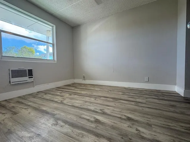 a view of empty room with window and wooden floor