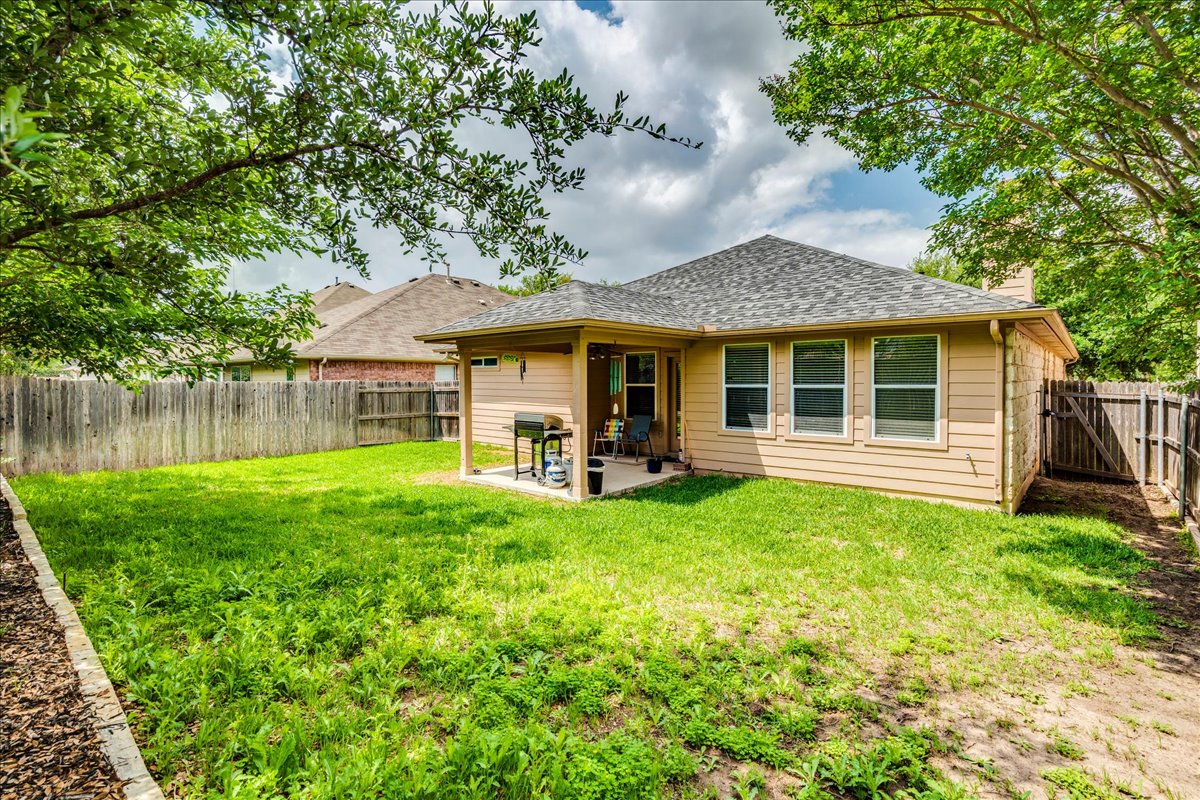 1151 Stone Rim Loop Buda, TX 78610 - Photo 28 of 35 The property features a fenced backyard with a grassy area and mature trees