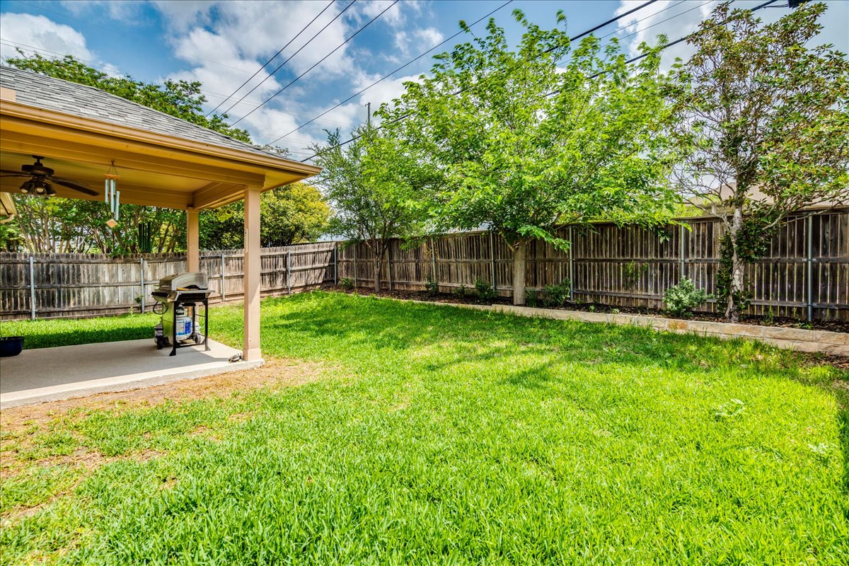 1151 Stone Rim Loop Buda, TX 78610 - Photo 30 of 35 The property features a private backyard with a covered patio, a spacious lawn, and a wooden fence