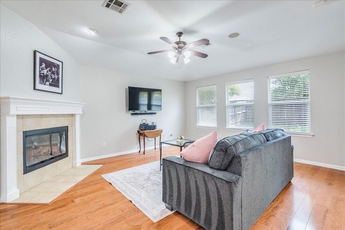 1151 Stone Rim Loop Buda, TX 78610 - Photo 6 of 35 This property features a living area with hardwood floors, a fireplace with a white mantel