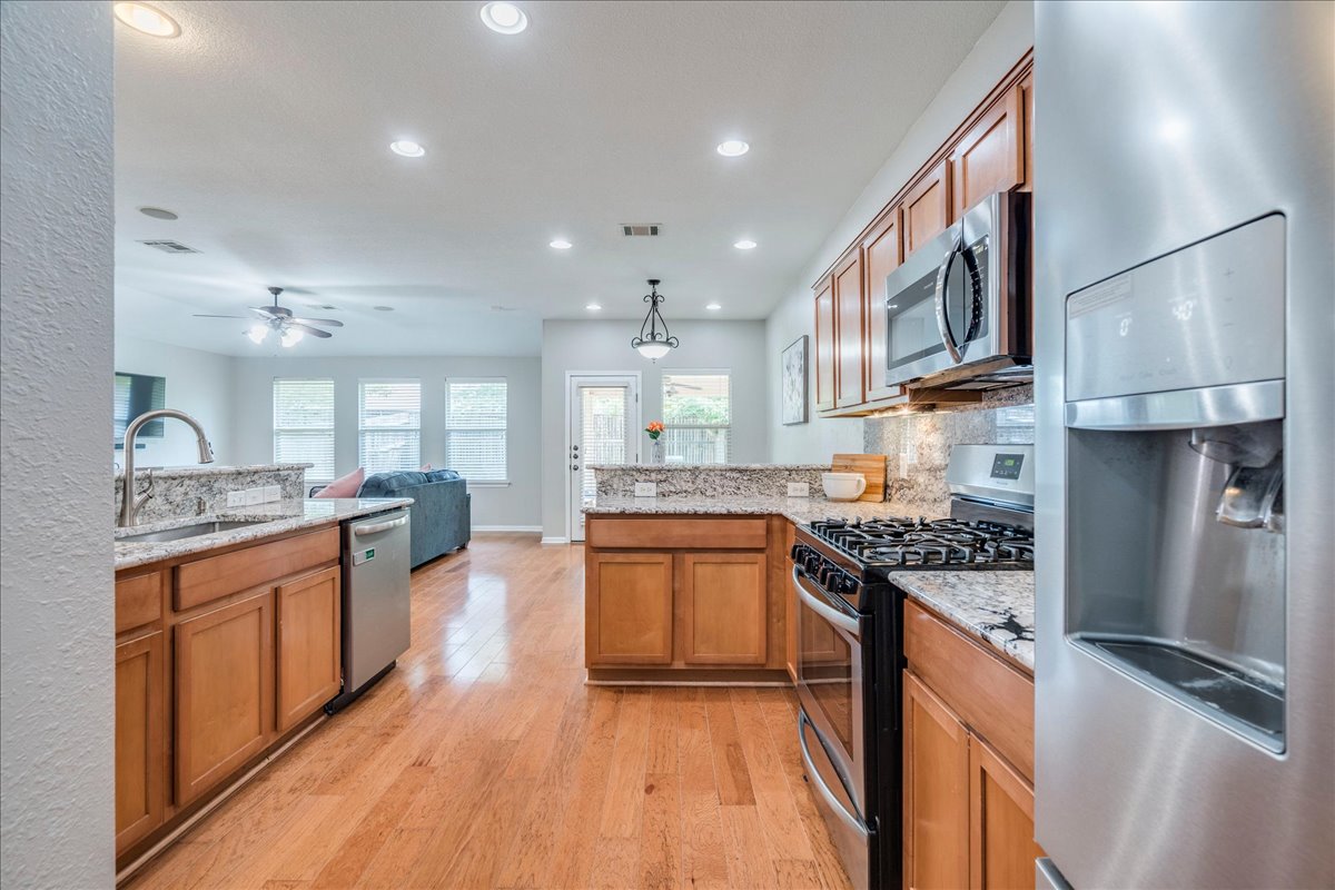 1151 Stone Rim Loop Buda, TX 78610 - Photo 10 of 35 The kitchen features wood cabinetry, granite countertops, stainless steel appliances, and hardwood floors