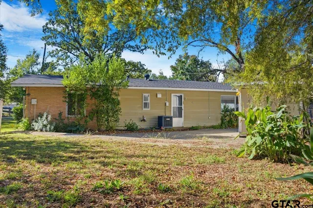 a view of a house with a yard and large tree