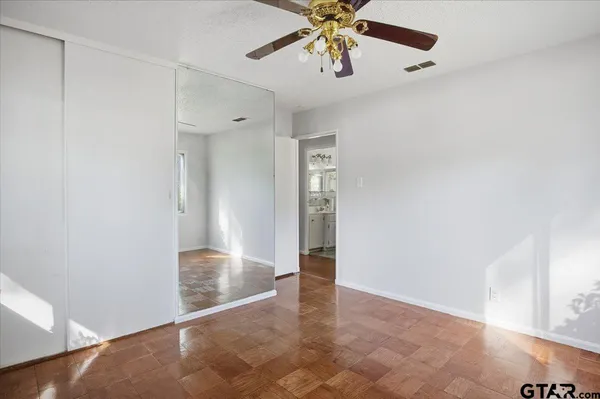 an empty room with closet and a chandelier fan
