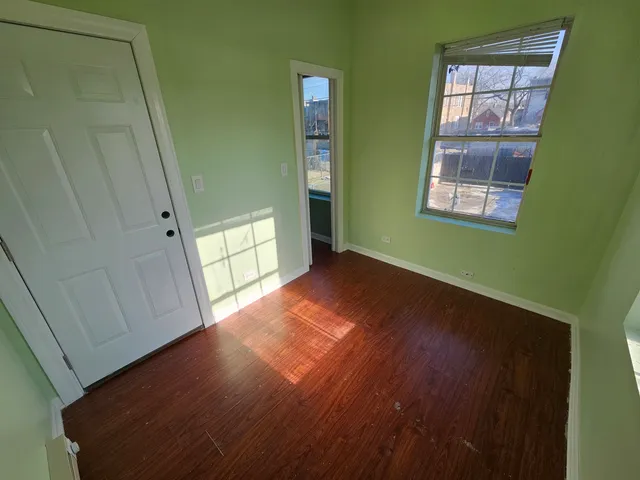 a view of empty room with window and wooden floor