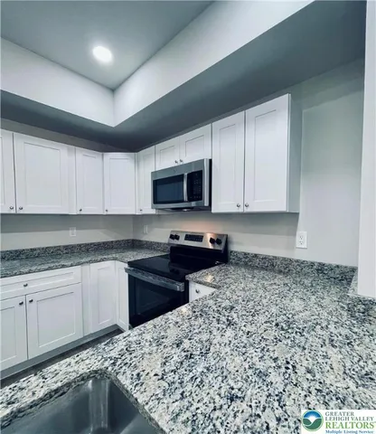 a kitchen with granite countertop a sink and a stove top oven