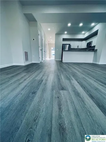a view of empty room with wooden floor and window