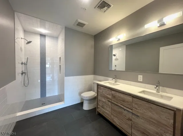 a bathroom with a double vanity sink toilet and shower