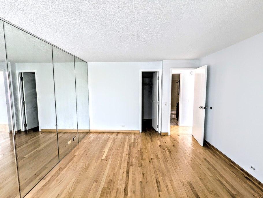 2555 Gross Point Road, Unit 407 Evanston, IL 60201 - Photo 7 of 10 a view of an empty room with wooden floor and a window