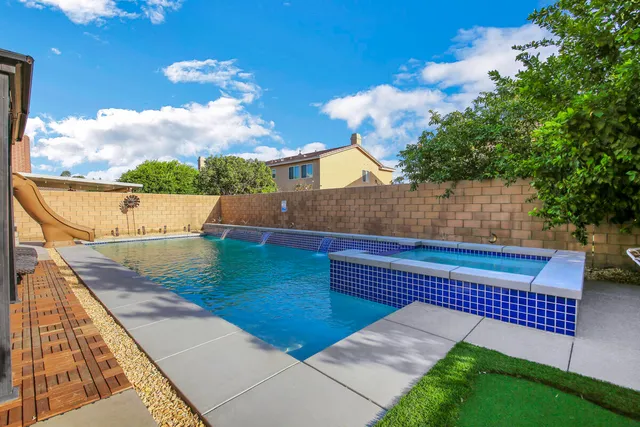 a view of a pool with a lawn chairs under an umbrella