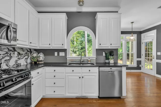 a kitchen with granite countertop a stove a sink and a granite counter tops with white cabinets