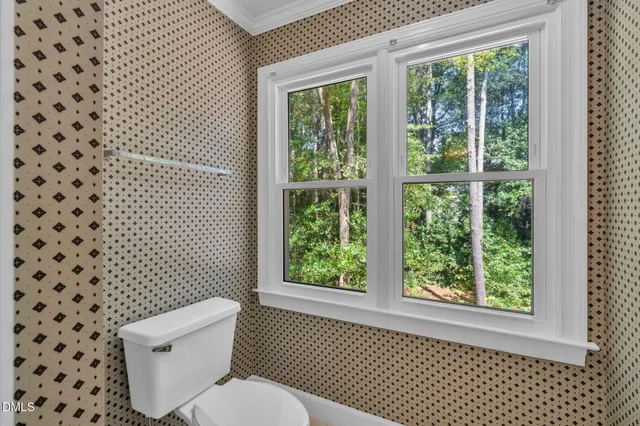 a white toilet sitting next to a window in a bathroom