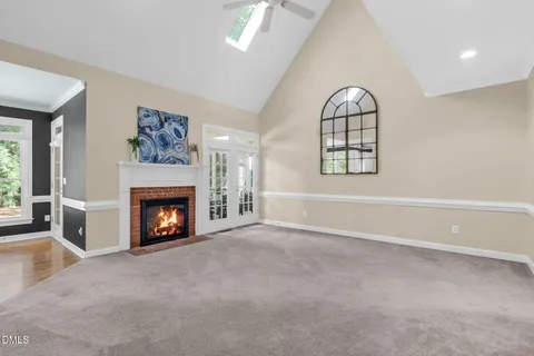 an empty room with windows fireplace and fans