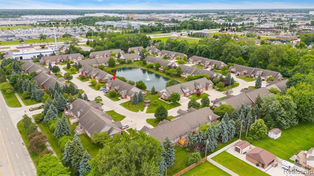 Expansive community featuring multiple residential buildings, a central pond with a water feature, mature landscaping, and well-maintained grounds