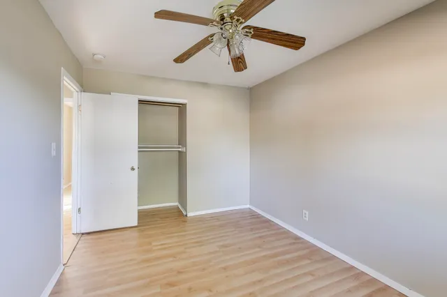 a view of an empty room with window and wooden floor
