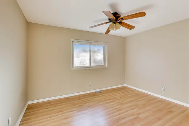 a view of empty room with wooden floor and ceiling fan
