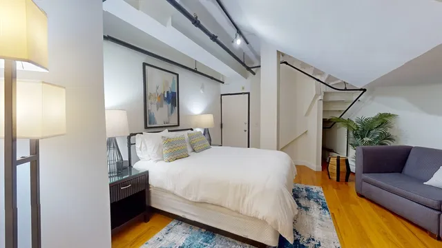 a bedroom with a bed couch and a potted plant