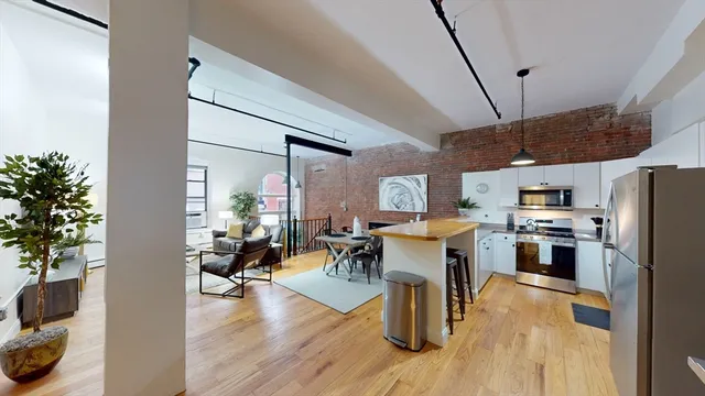 a living room with stainless steel appliances kitchen island granite countertop furniture wooden floor and a kitchen view