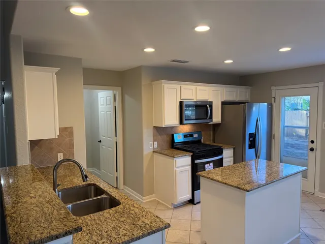a kitchen with granite countertop a sink a stove and a refrigerator