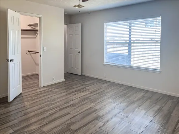 an empty room with wooden floor and windows