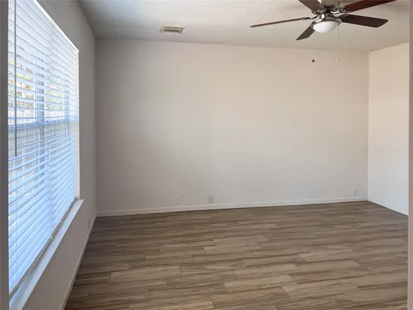 a view of an empty room with a window and wooden floor