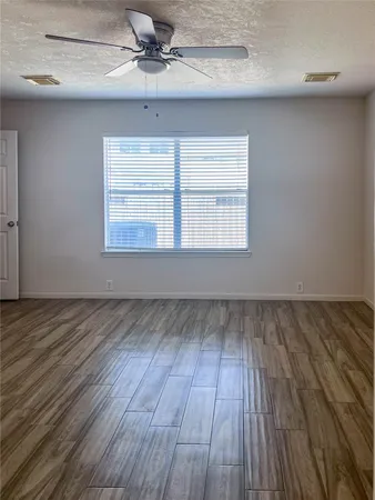 a view of an empty room with a window and wooden floor