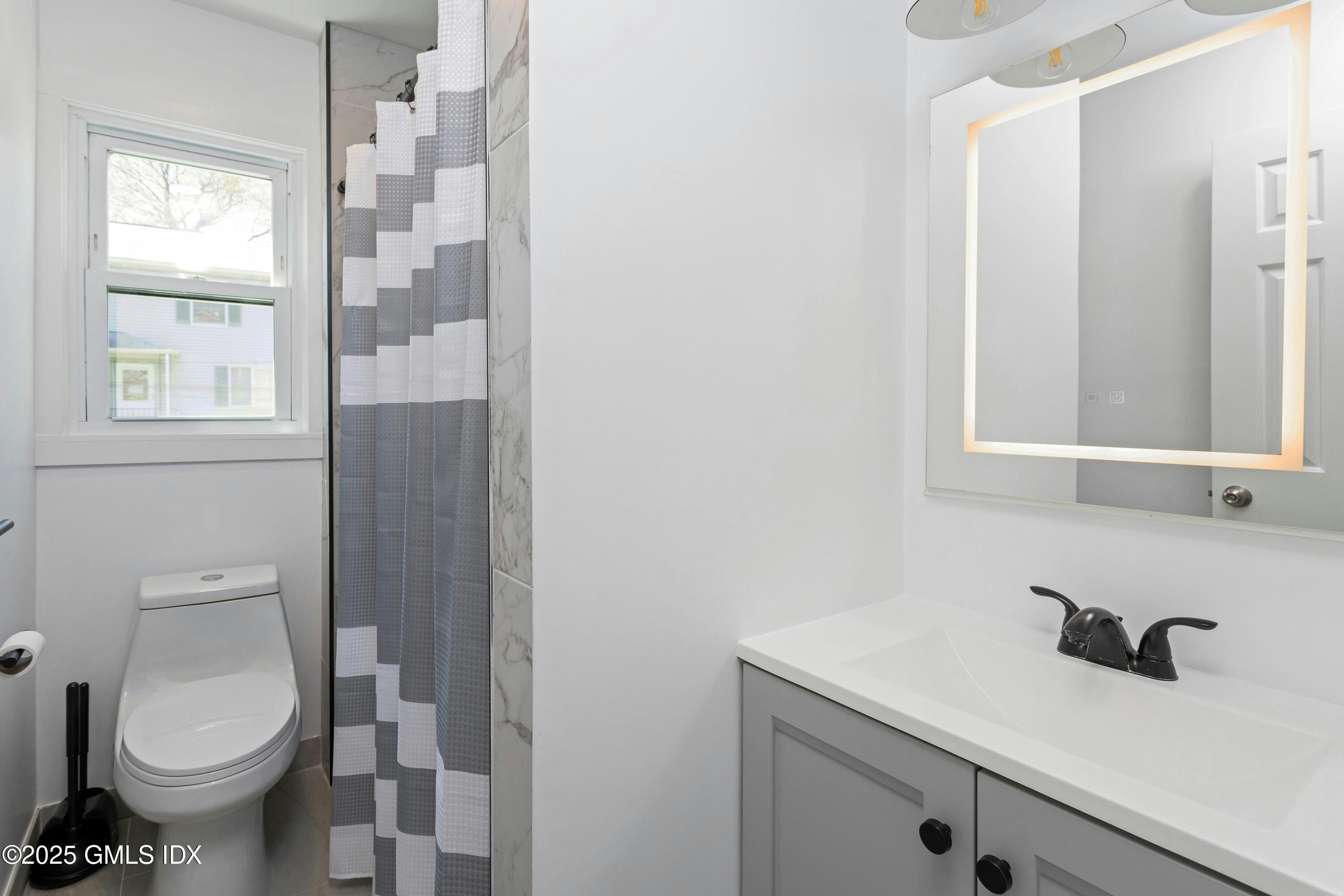 171 1/2 Henry Street, Unit A Greenwich, CT 06830 - Photo 13 of 25 a bathroom with a toilet sink and mirror