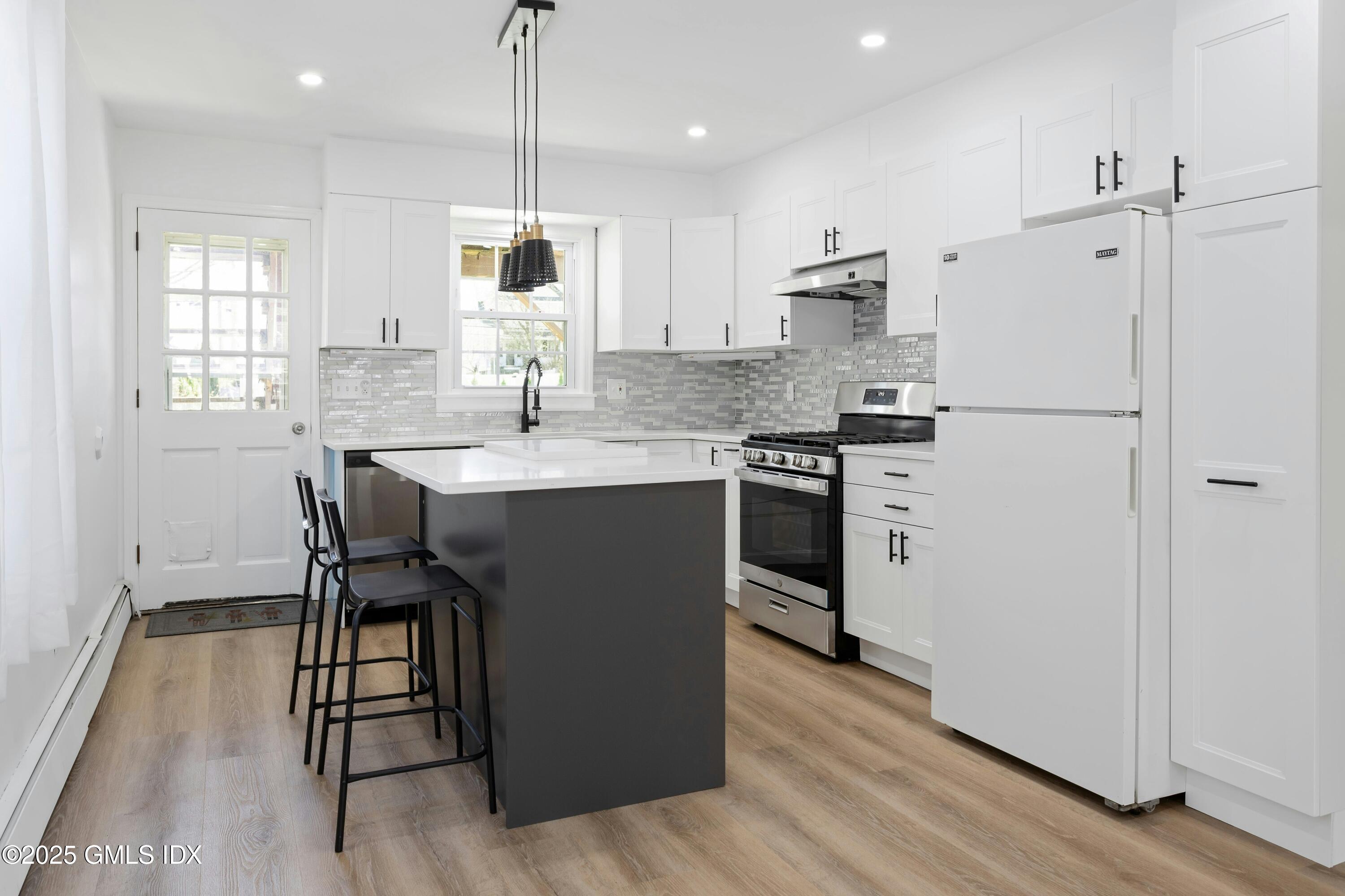 171 1/2 Henry Street, Unit A Greenwich, CT 06830 - Photo 6 of 25 a kitchen with stainless steel appliances granite countertop a table chairs refrigerator and sink