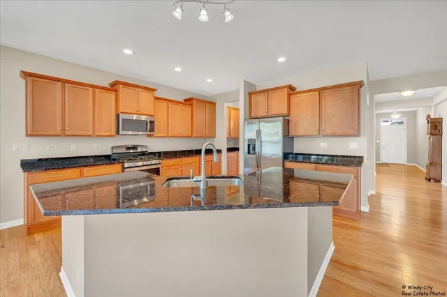 a kitchen with stainless steel appliances granite countertop a stove a sink and a refrigerator