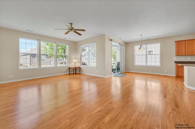 a view of empty room with wooden floor and fan
