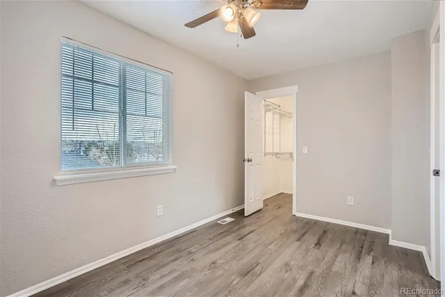 an empty room with wooden floor cabinet and windows