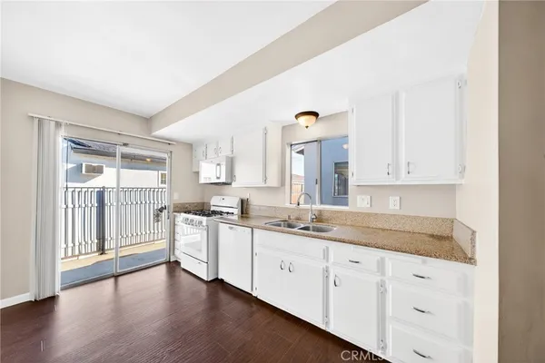 a large kitchen with granite countertop a sink and dishwasher refrigerator a oven with wooden floors