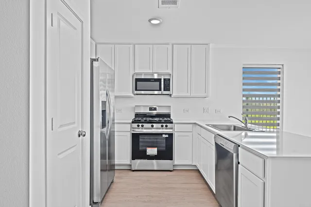 a view of kitchen with white cabinets and window