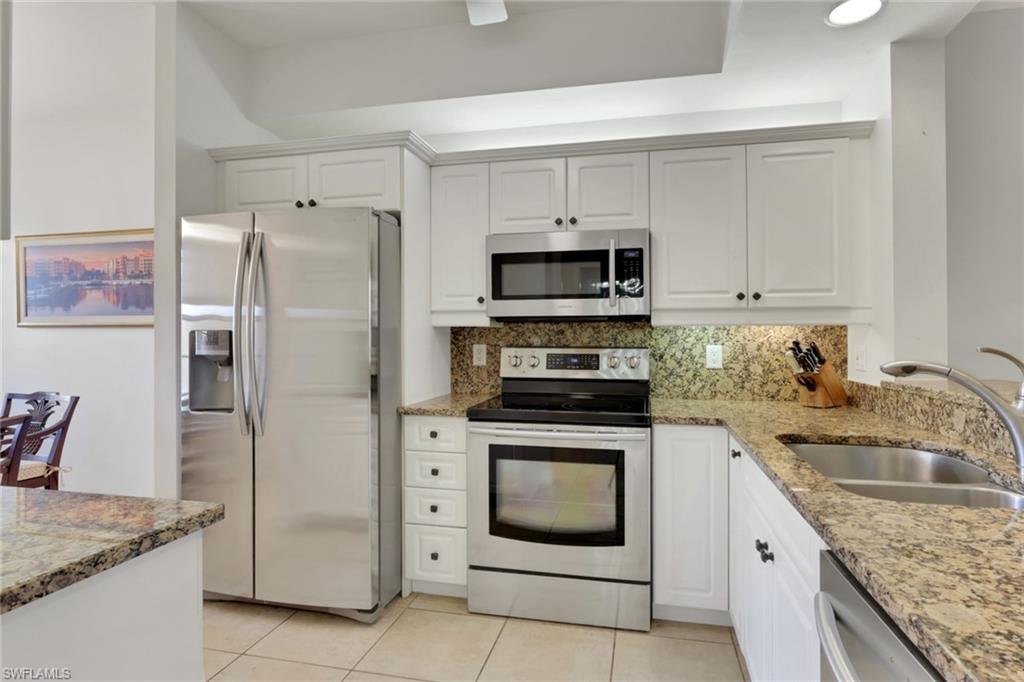 401 Bayfront Place, Unit 3207 Naples, FL 34102 - Photo 9 of 22 Kitchen featuring light stone countertops, stainless steel appliances, tasteful backsplash, and white cabinetry