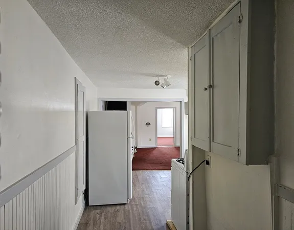 a view of a hallway with a refrigerator and a window
