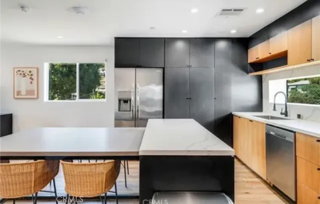 a kitchen with stainless steel appliances a kitchen island sink refrigerator and window