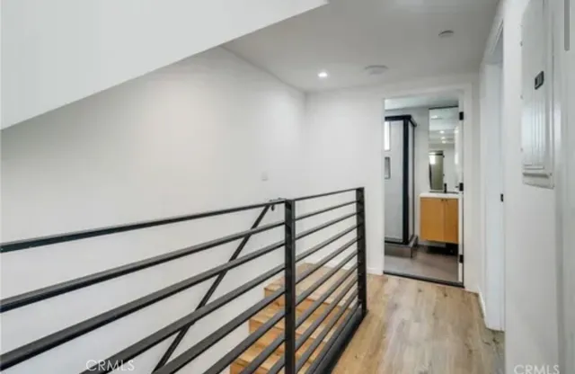 a view of a hallway with wooden floor and a bedroom