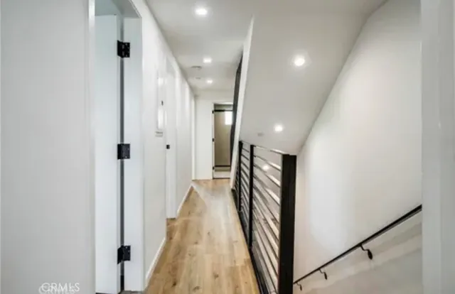 a view of a hallway with wooden floor and staircase