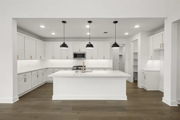a large white kitchen with stainless steel appliances kitchen island a sink a stove and a refrigerator