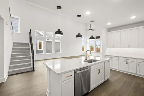 a kitchen with stainless steel appliances granite countertop a sink a oven a refrigerator and white cabinets with wooden floor