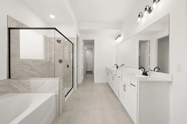 a bathroom with a double vanity sink a large mirror and a bathtub