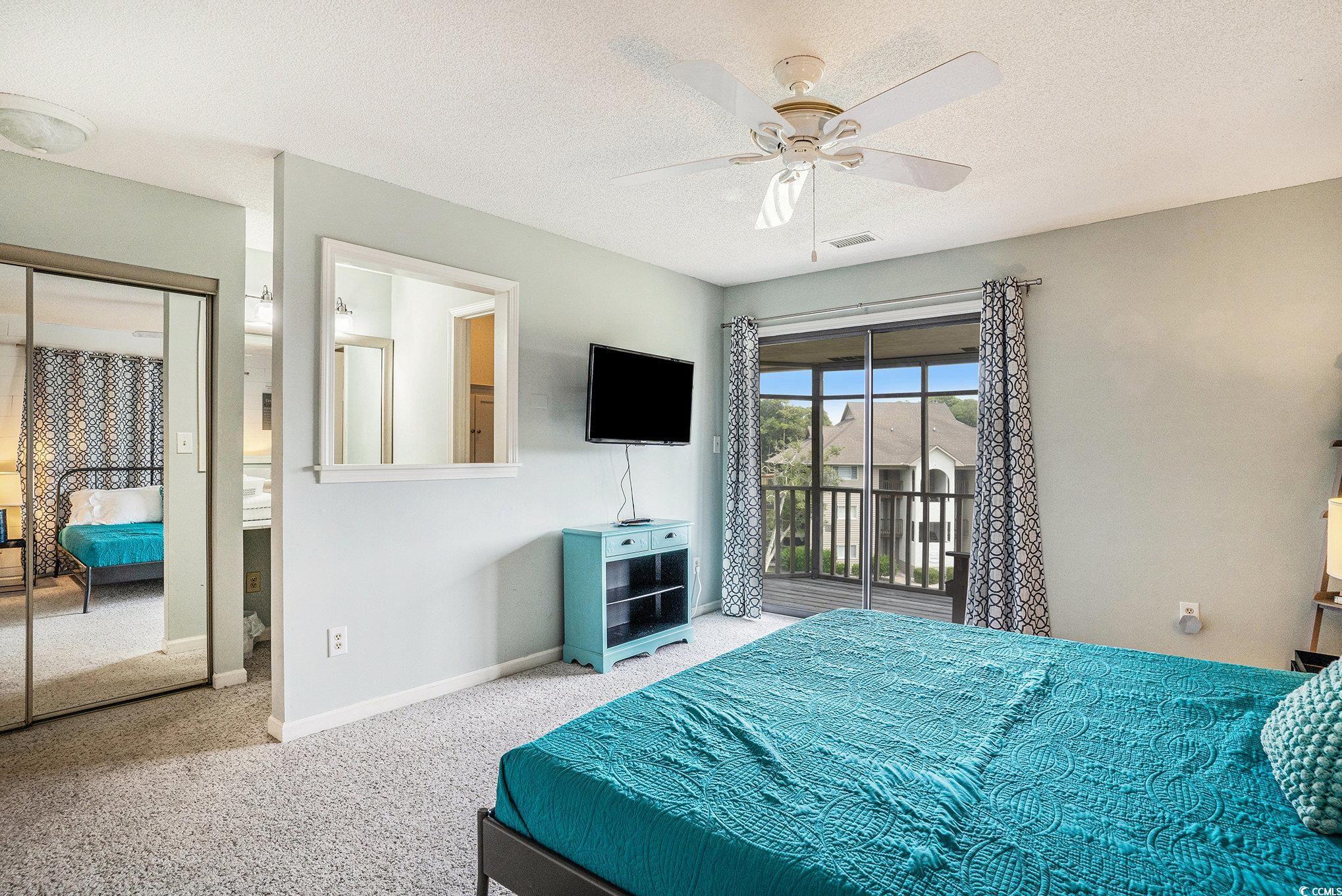 815 Colony Place, Unit 15F Sunset Beach, NC 28468 - Photo 14 of 34 Bedroom featuring access to outside, carpet floors, a textured ceiling, a ceiling fan, and a closet