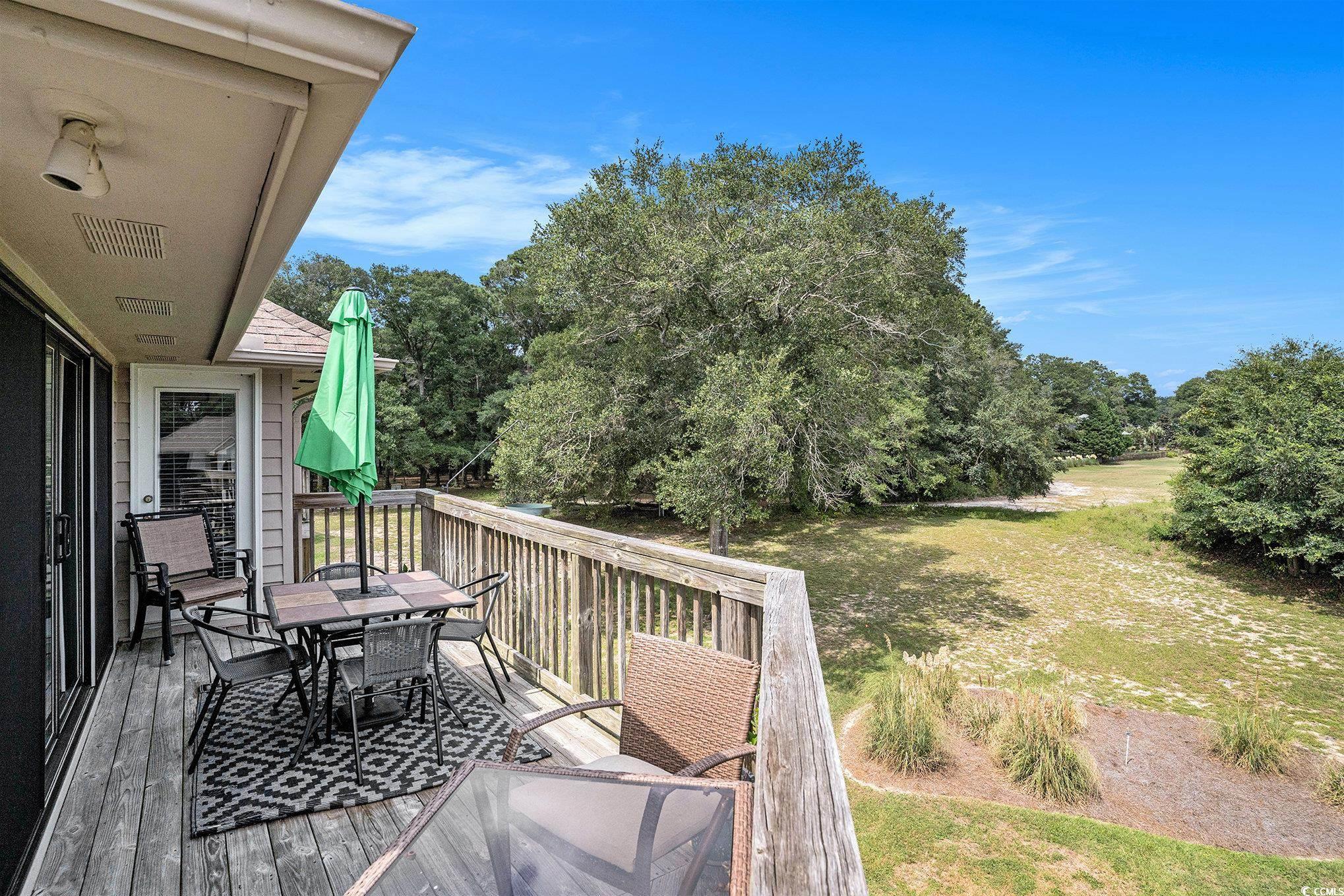 815 Colony Place, Unit 15F Sunset Beach, NC 28468 - Photo 21 of 34 Wooden deck with outdoor dining area, view of wooded area, and a lawn