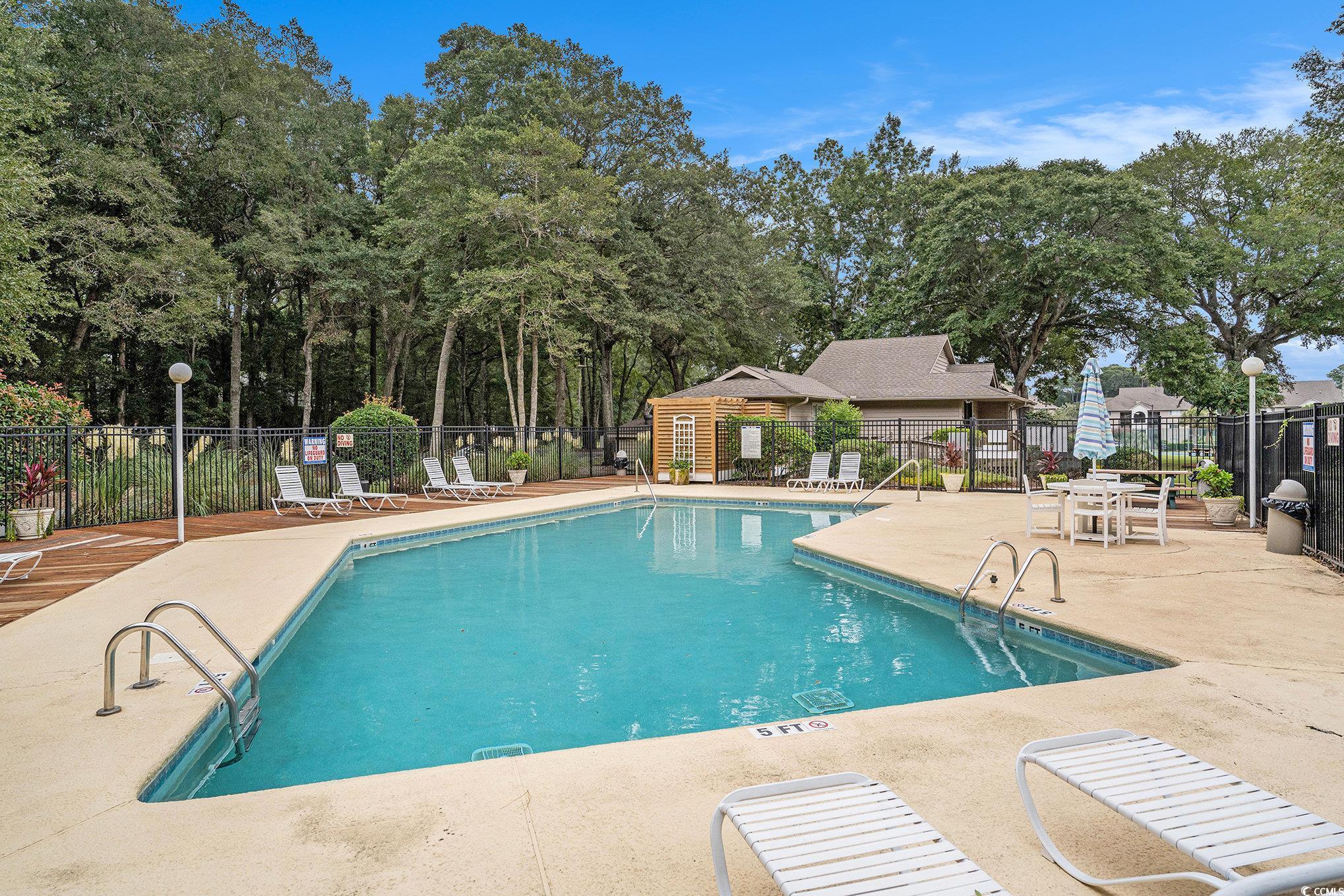 815 Colony Place, Unit 15F Sunset Beach, NC 28468 - Photo 22 of 34 Community pool featuring a patio area and view of scattered trees